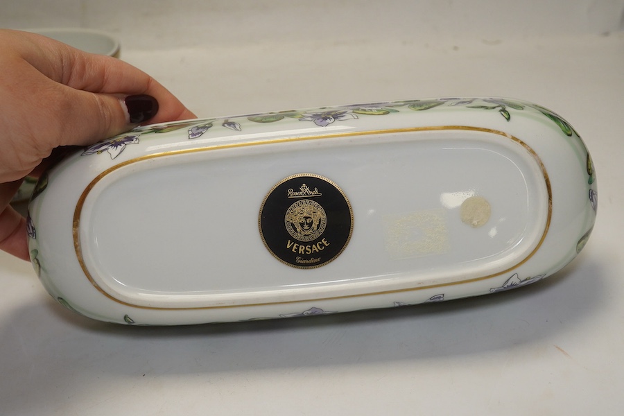 Six Rosenthal for Versace porcelain items; a boxed chocolate cup and saucer, four oblong serving dishes, longest 23cm, and a boxed miniature timepiece, 8.5cm high. Condition - good.